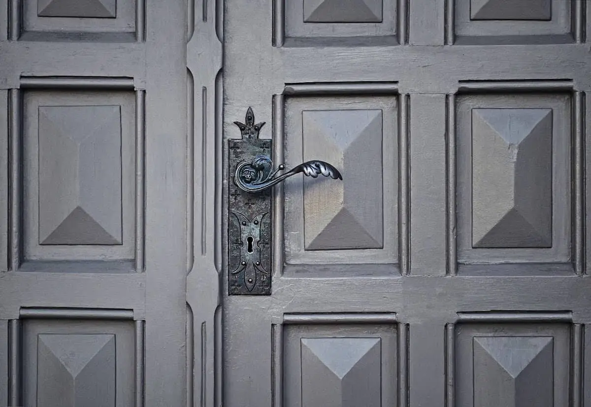 Cerradura con manija de puerta en espiral en una puerta gris con motivos geométricos.