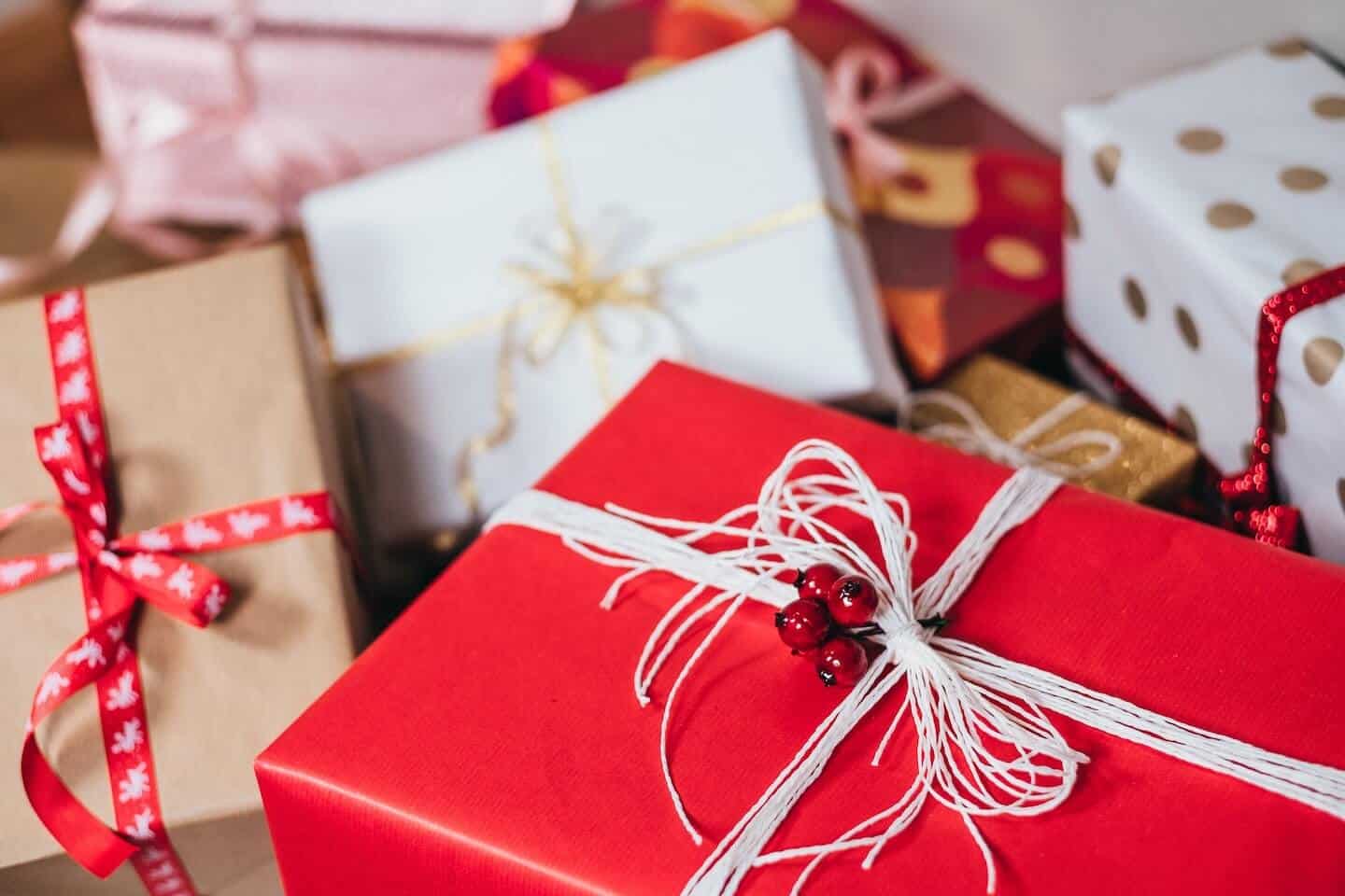 Varias cajas de regalo envueltas en cintas y papel de regalo rojo, blanco y marrón.